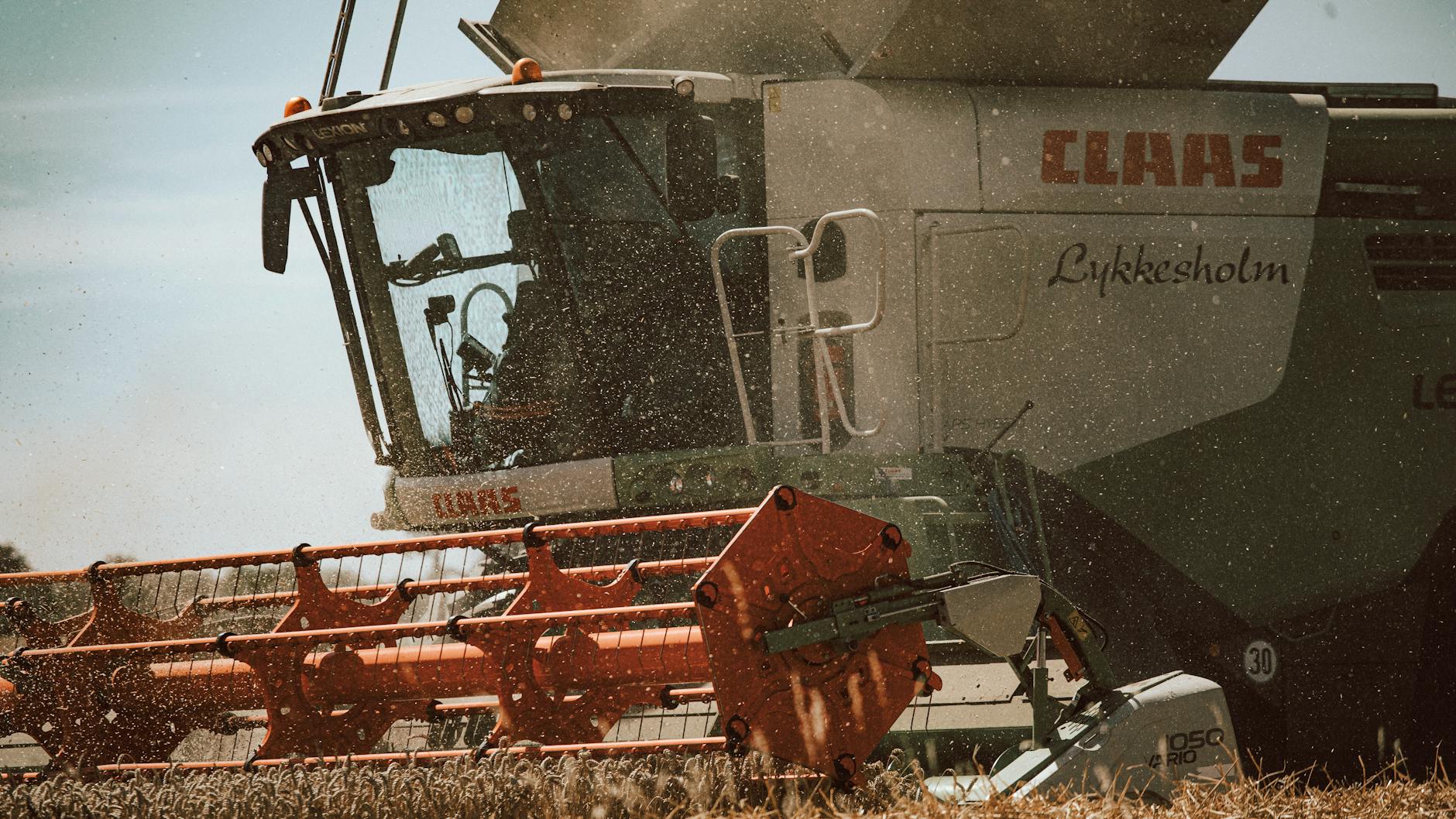 Kombajn podczas żniw z bliska, ujęcie sit i nowoczesnego systemu czyszczenia