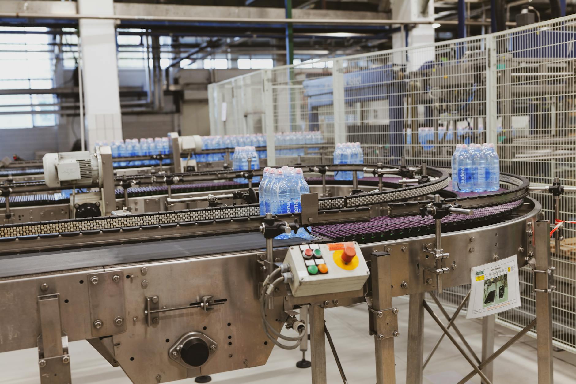 Plastikowe butelki na taśmowym podajniku w nowoczesnej rozlewni