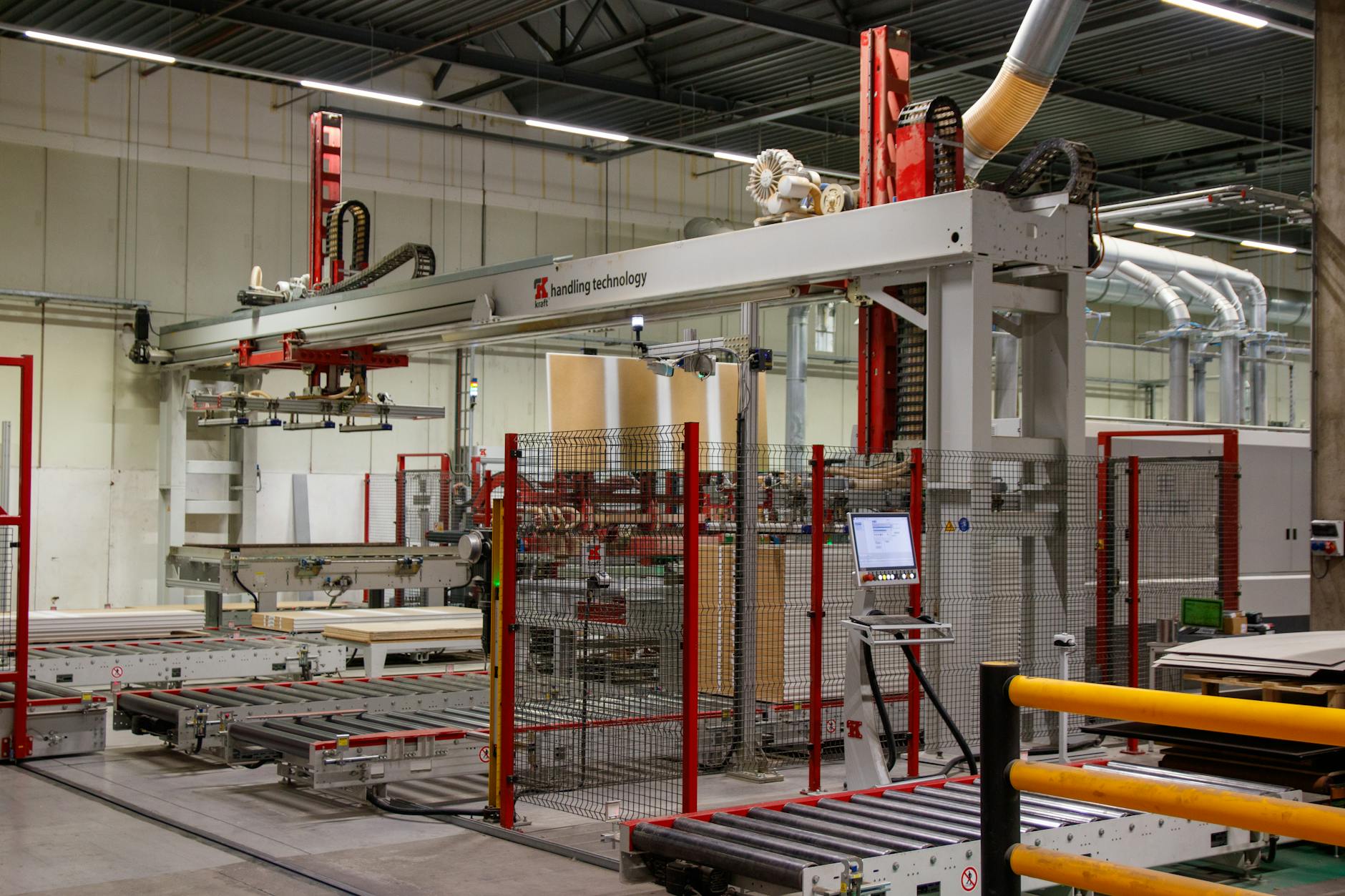 Robotyczne ramię przy taśmociągu w hali produkcyjnej