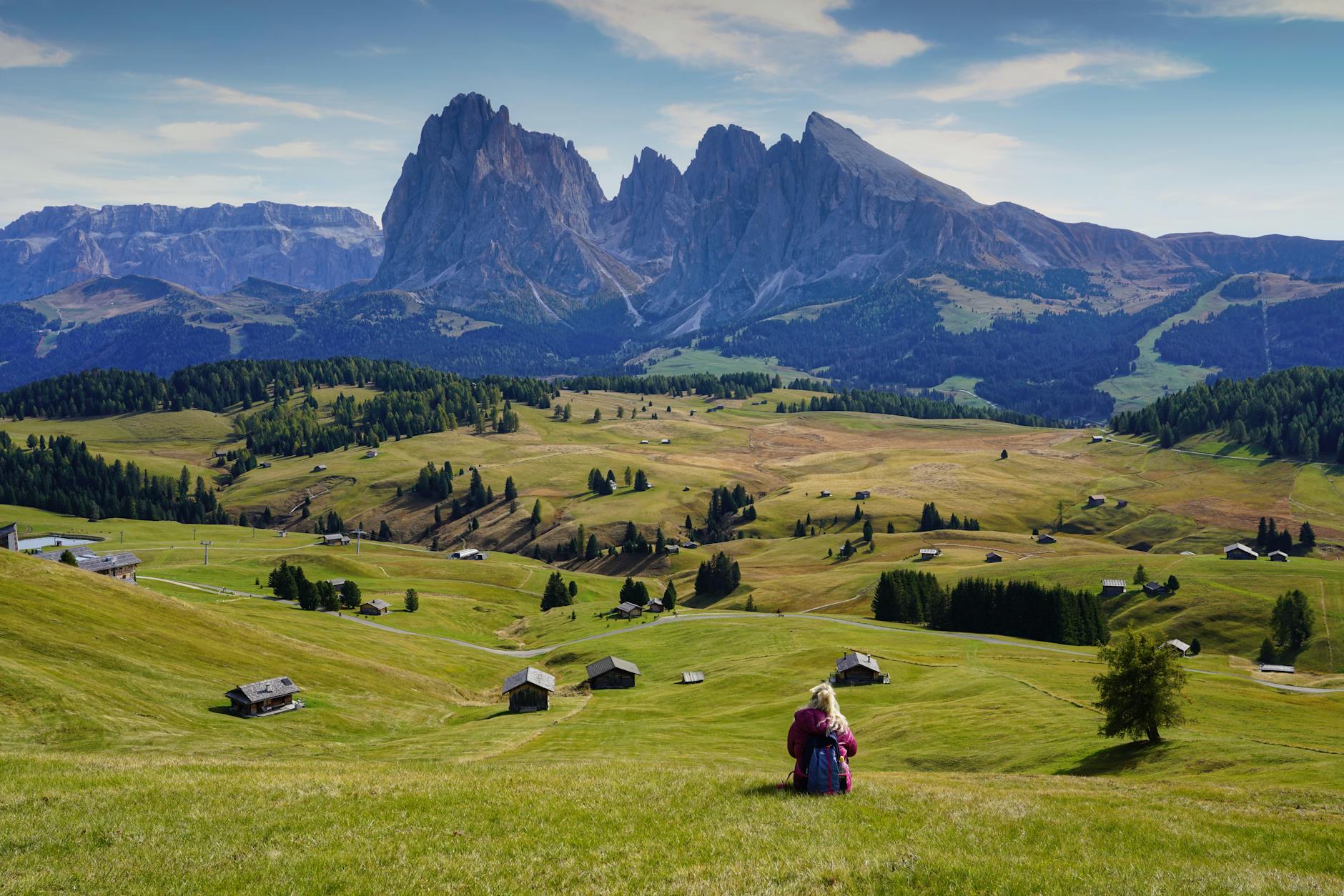 Kobieta podziwia Dolomity Brenta, siedząc na zielonej górskiej łące