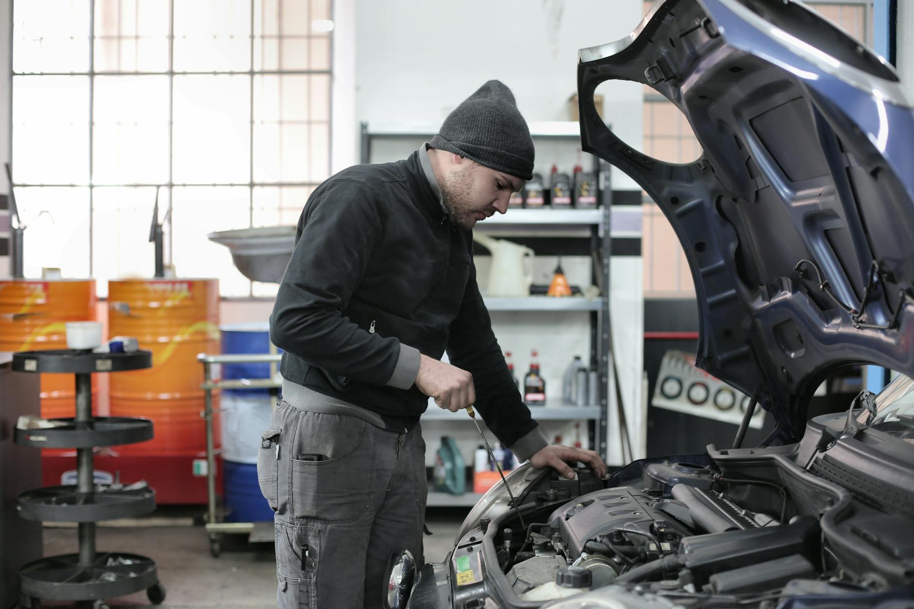 Mechanik w garażu sprawdza silnik samochodu przed pierwszym rozruchem Mechanik w garażu sprawdza silnik samochodu przed pierwszym rozruchem
