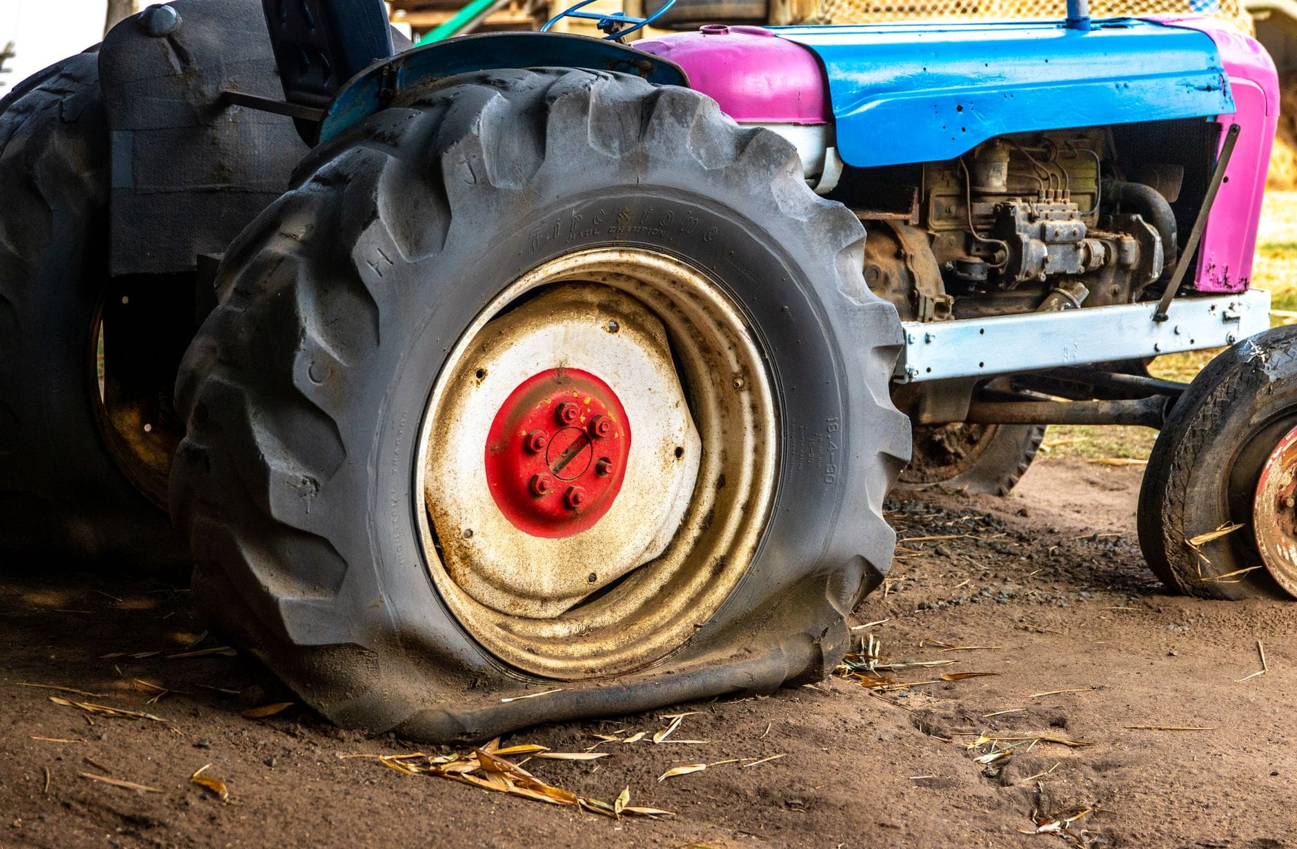 Ciągnik rolniczy z przebitą oponą na podwórzu gospodarstwa